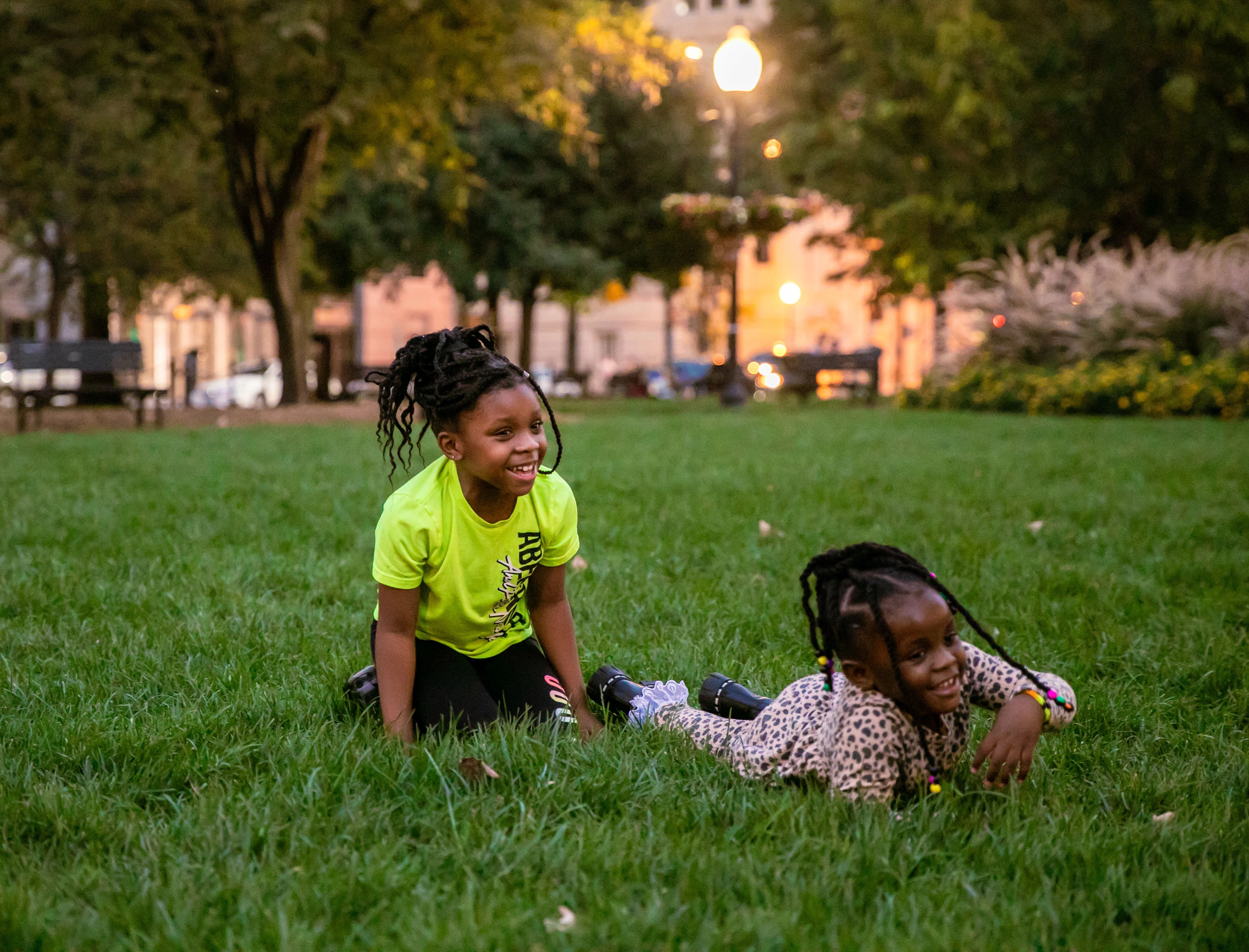 two young black children play on a grass lawn