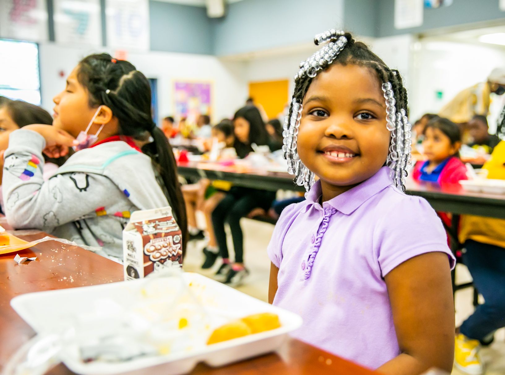 smiling girl in elementary room classroom sitting at her desk