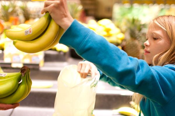 Kid choosing bananas at grocery store