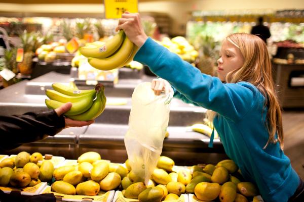 girl picking up bananas in the grocery store