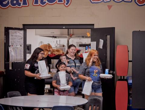A mom and her three kids pick up bagged lunches from their local school