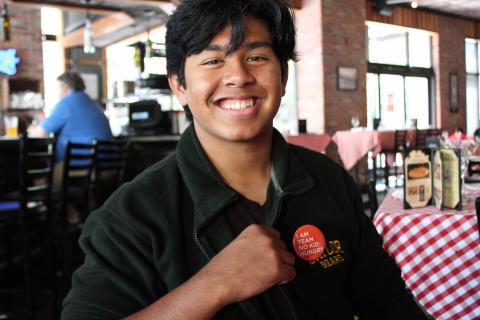Image of Student smiling and wearing an orange "Team No Kid Hungry" pin