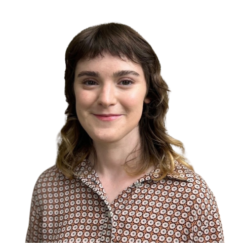 Headshot of a young woman with short, wavy hair and bangs, wearing a patterned blouse with a geometric floral design in brown and white. She is smiling against a white background.