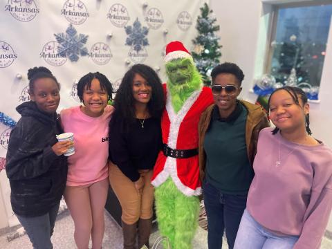 Passion and her family taking a picture with the Grinch at Christmas time